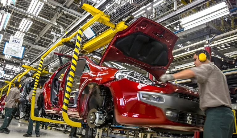Línea de montaje de autos en planta industrial con operarios y vehículos en producción, representando el crecimiento de la industria automotriz en Argentina