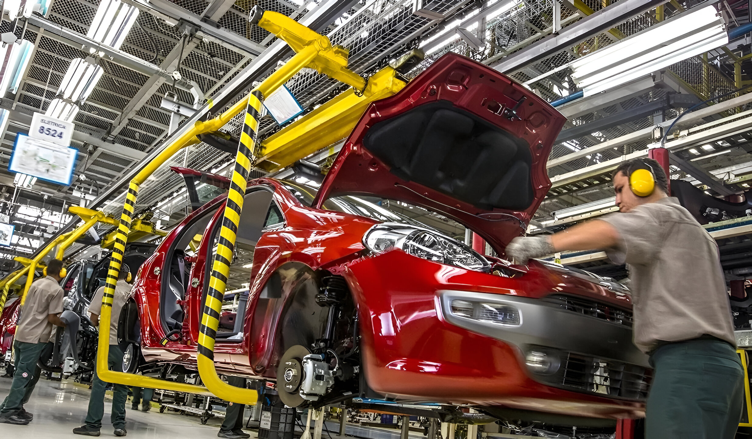 Línea de montaje de autos en planta industrial con operarios y vehículos en producción, representando el crecimiento de la industria automotriz en Argentina