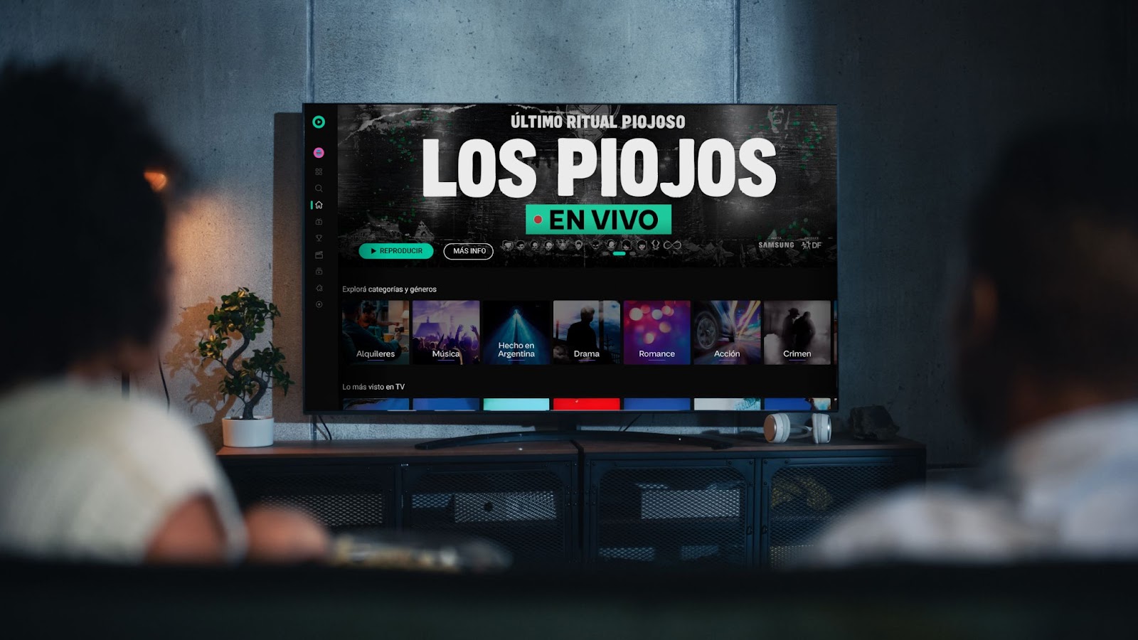 Pantalla de TV con la transmisión en vivo del último recital de Los Piojos por Flow, vista desde el living con dos personas observando el show