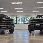 Vista frontal de las camionetas Ford F-150 Tremor y Ford Bronco exhibidas en un showroom, reconocidas por los Premios Autocosmos como los mejores vehículos del año en sus categorías