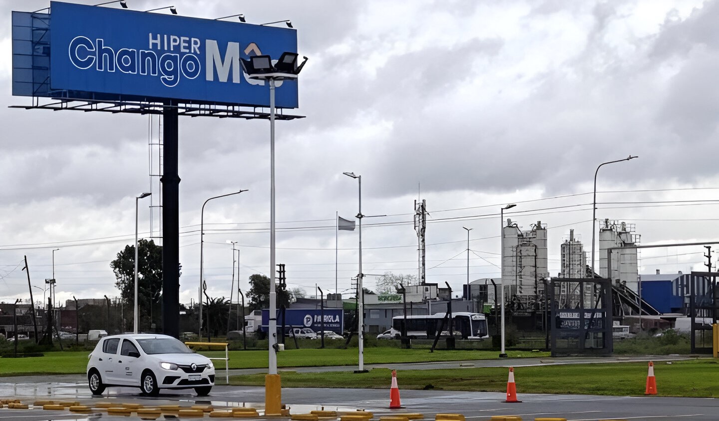 "Auto blanco en circuito de entrenamiento frente a un cartel de Hiper ChangoMás, durante una jornada del programa Conduciendo Oportunidades impulsado por Mujeres al Volante