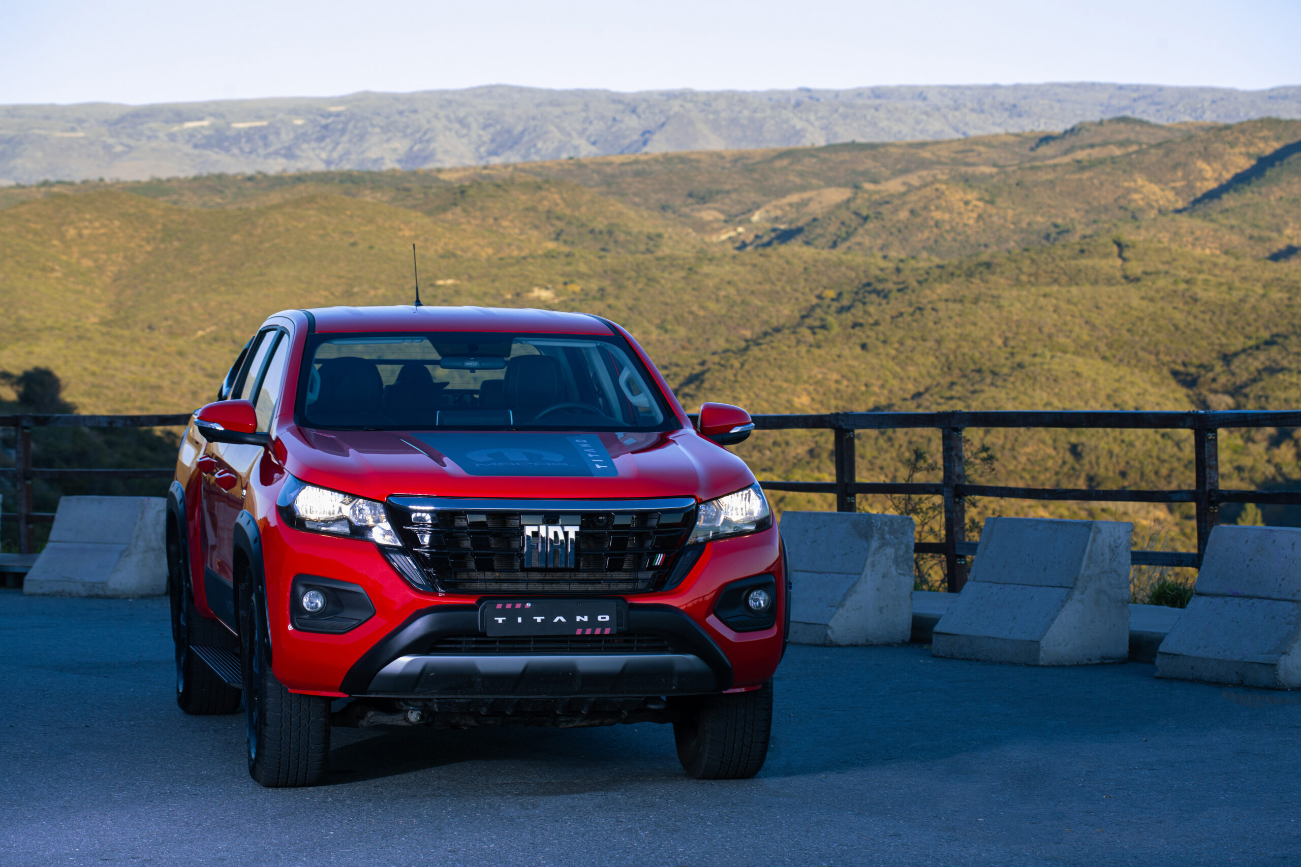 Vista frontal de la nueva Fiat Titano roja, la pick-up fabricada en Argentina, estacionada con paisaje de montañas de fondo