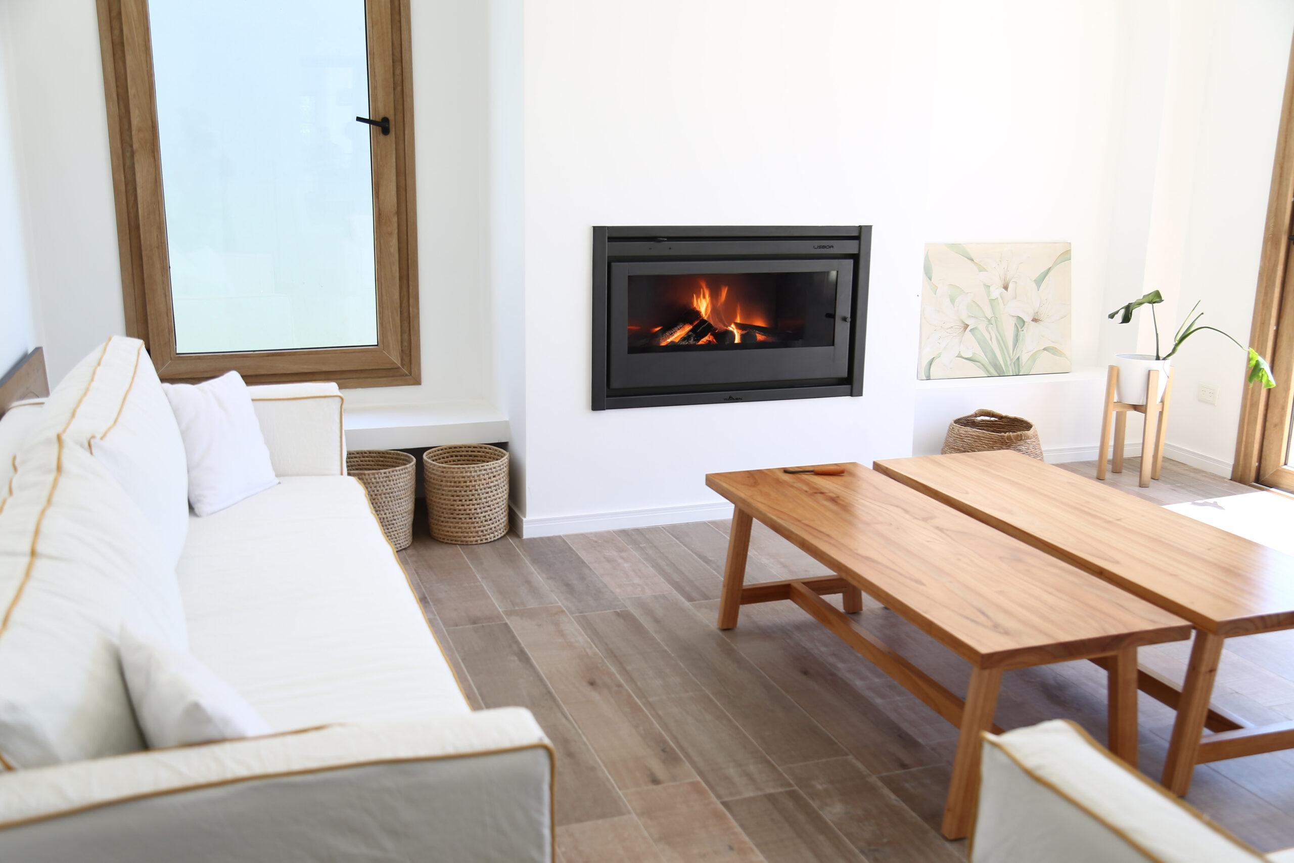 Calefactor Tromen Black encendido en un living moderno con decoración minimalista y muebles de madera clara