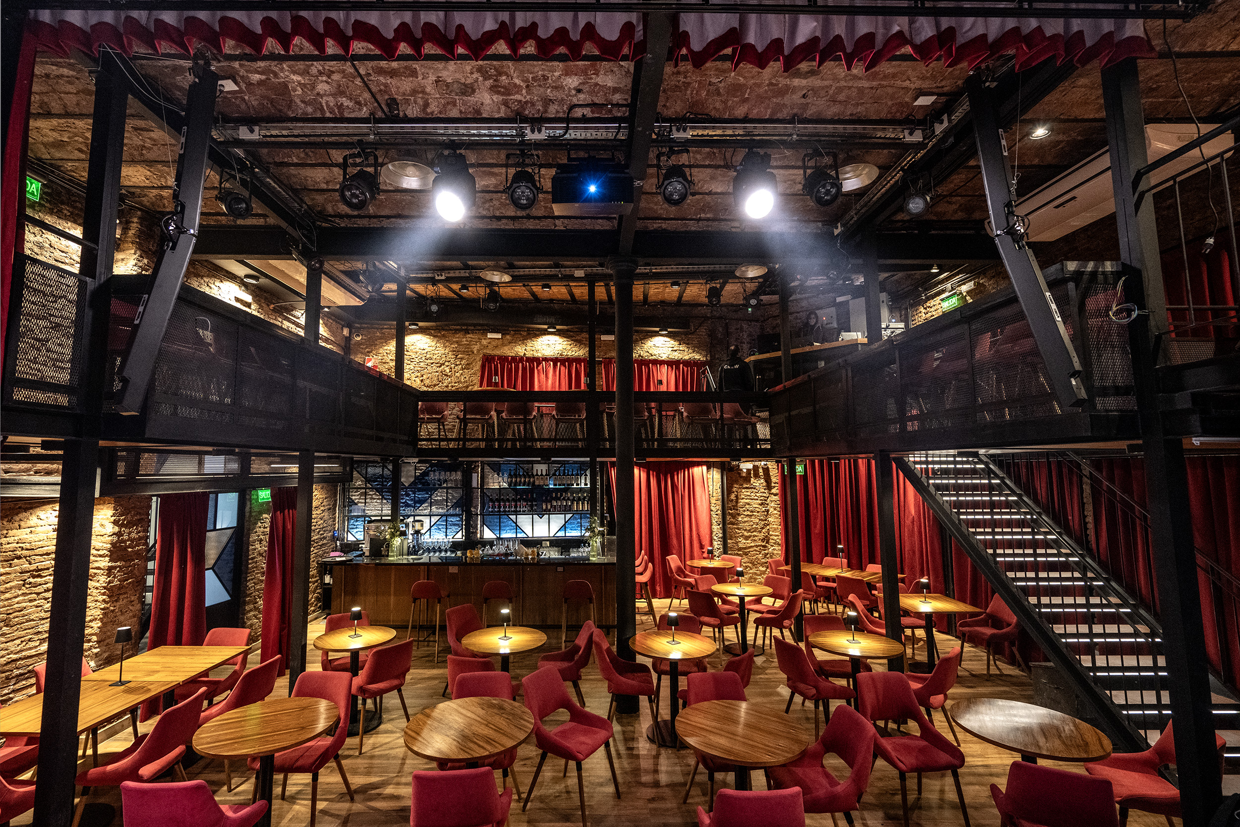 Vista del interior de La Carbonera en San Telmo, con mesas redondas, sillas rojas, iluminación cálida y una atmósfera íntima para shows en vivo