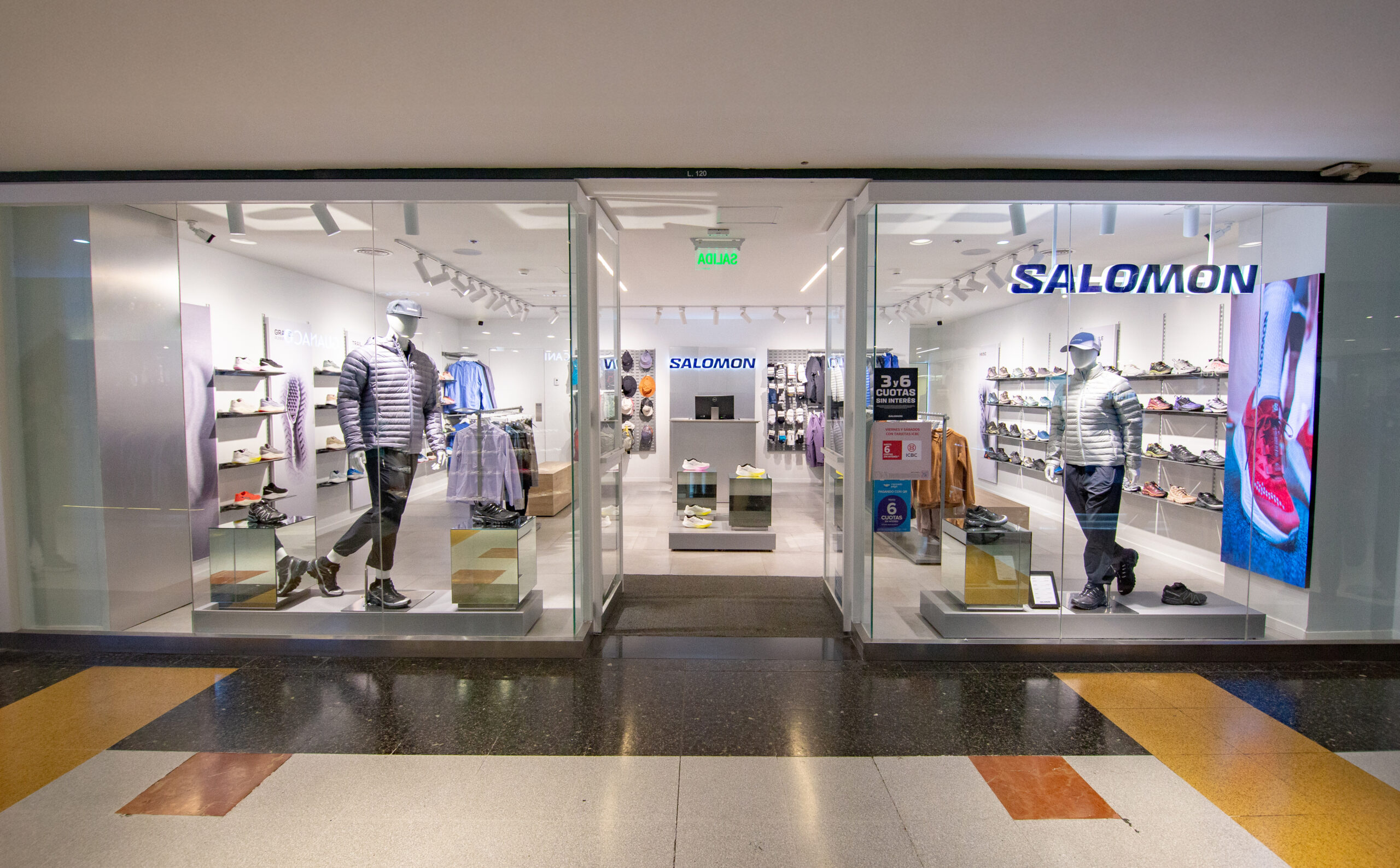 Vista frontal de la tienda Salomon en el shopping Patio Olmos de Córdoba, con indumentaria y calzado deportivo exhibido en vidrieras modernas