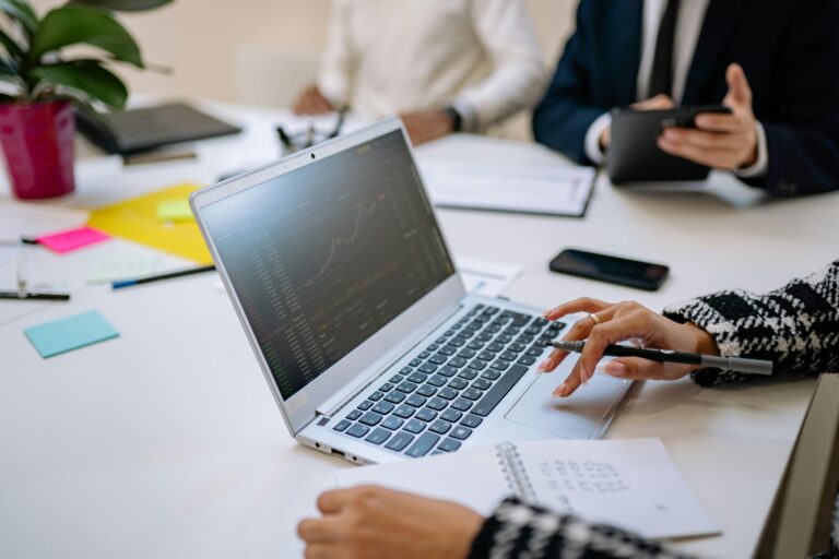 Persona analizando datos de ventas y facturación en una notebook durante una reunión de negocios, simbolizando la digitalización de procesos en pequeños comercios