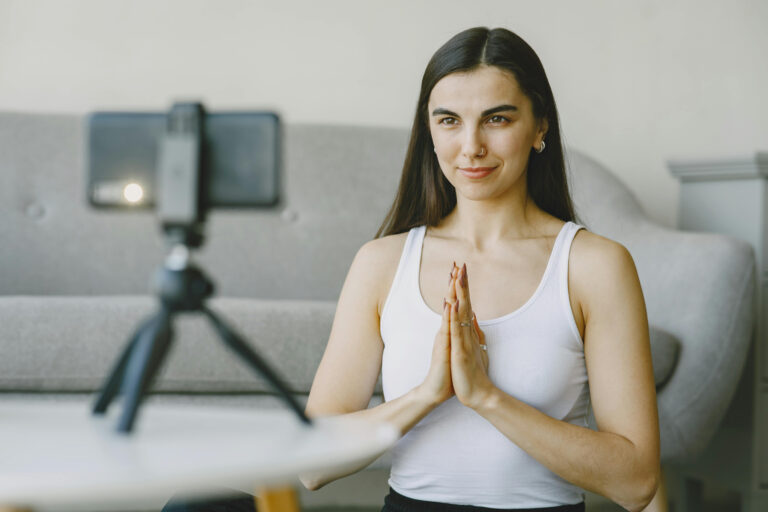 Mujer en posición de meditación frente a una cámara, grabando una clase de mindfulness