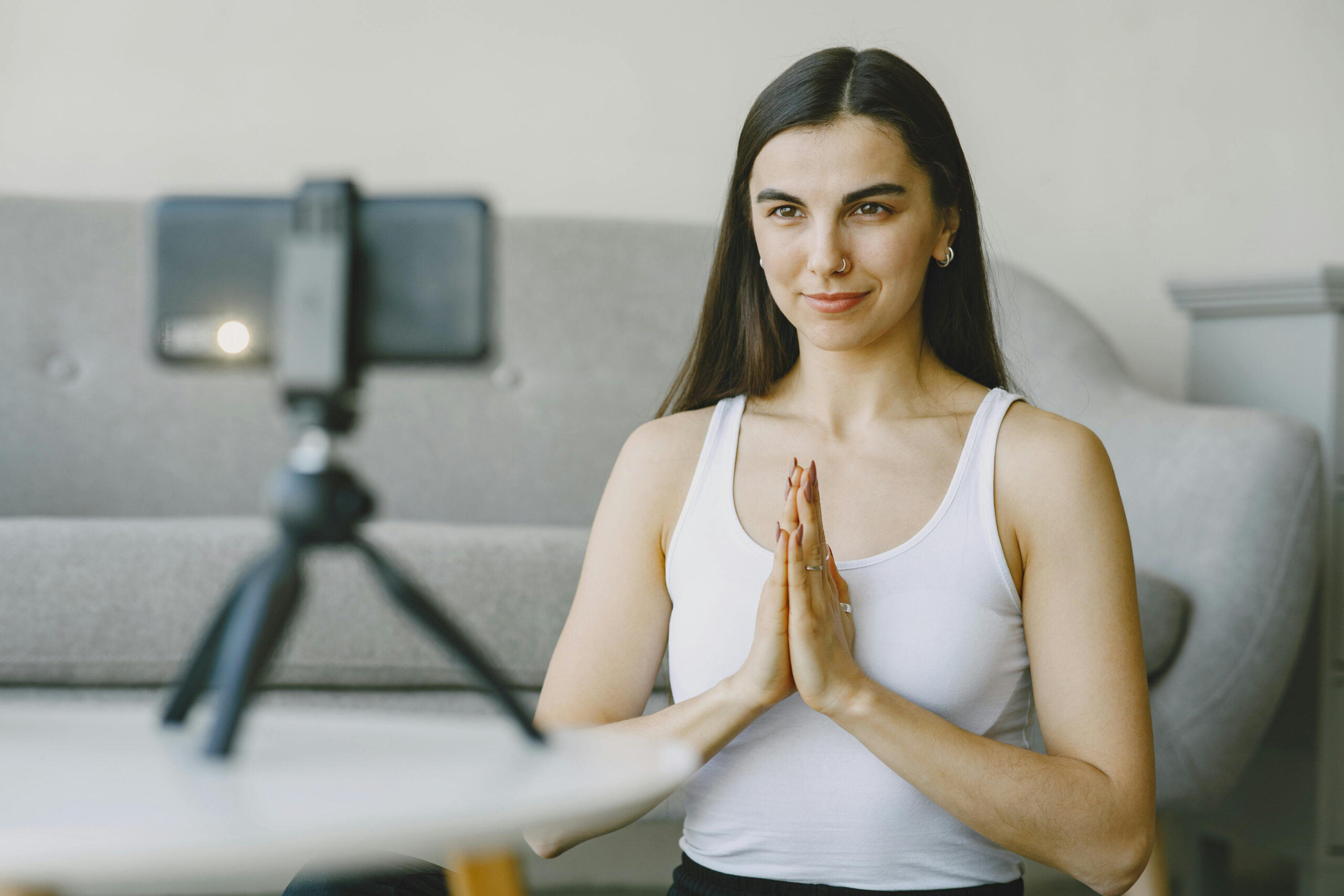 Mujer en posición de meditación frente a una cámara, grabando una clase de mindfulness