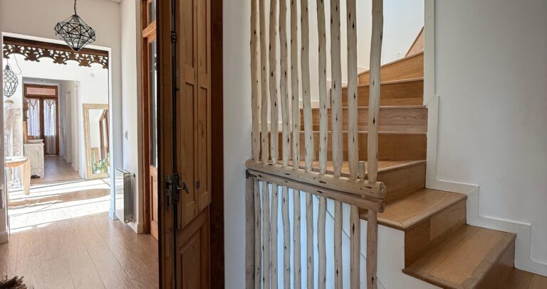 Panel divisor de madera rústica que delimita una escalera sin bloquear la luz ni el paso visual