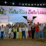 Grupo de personas posando frente al cartel de entrada de “Entre Ríos, Entre Viñas”, con iluminación nocturna y ambiente festivo