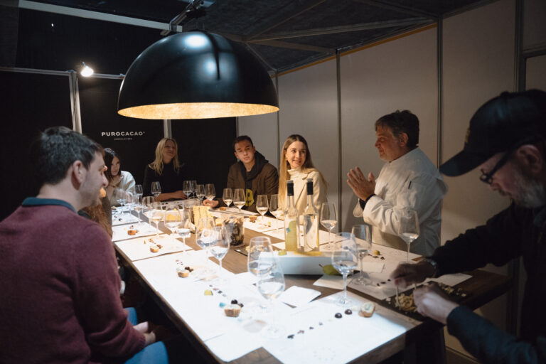 Personas participando de una cata exclusiva de chocolates en el Atelier de PUROCACAO, con copas de vino y maridajes guiados por un experto