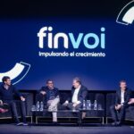 Disertantes conversando en el escenario durante el evento Finvoi, con el logo proyectado de fondo y ambiente profesional