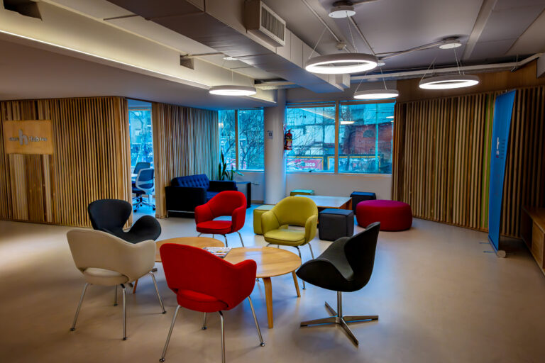 Sala de coworking de SMS HUB con sillones de colores y mesas redondas en un entorno moderno y luminoso