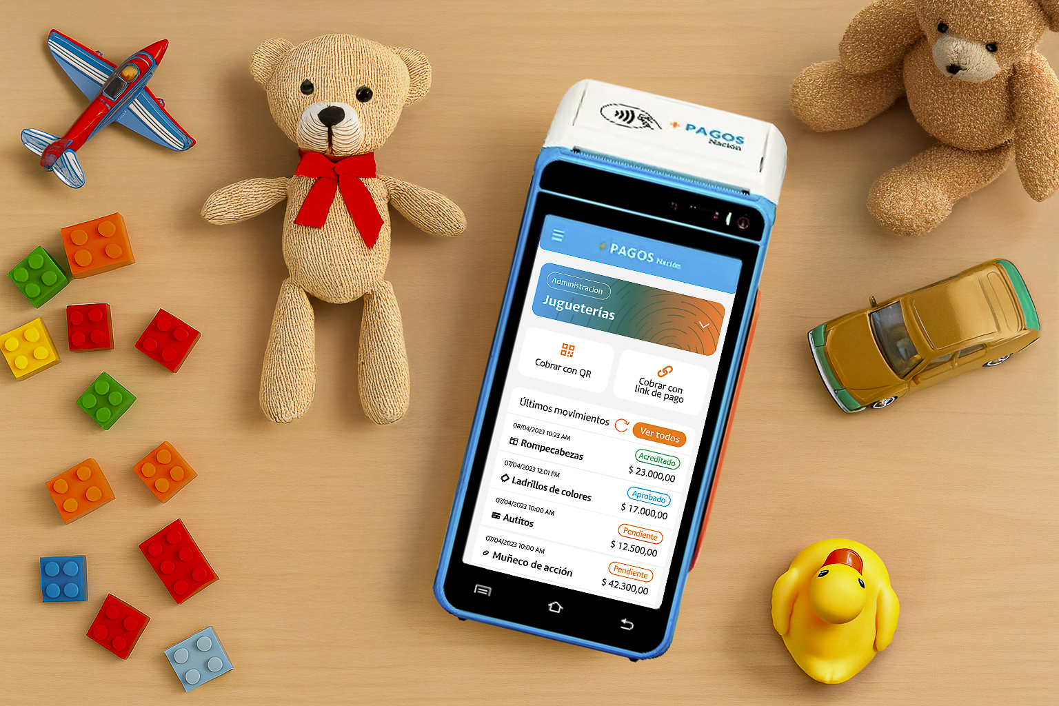 Dispositivo de pagos electrónicos de Banco Nación sobre una mesa con juguetes infantiles, utilizado para compras por el Día del Niño
