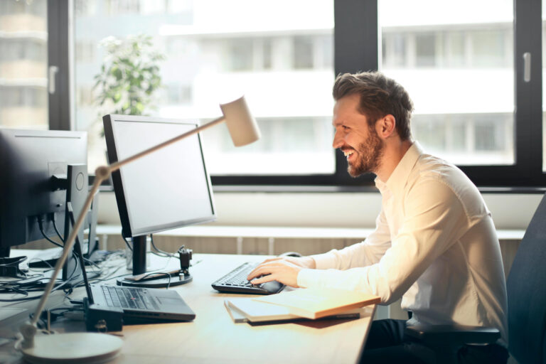 Hombre trabajando frente a una computadora en un entorno de oficina moderno y luminoso