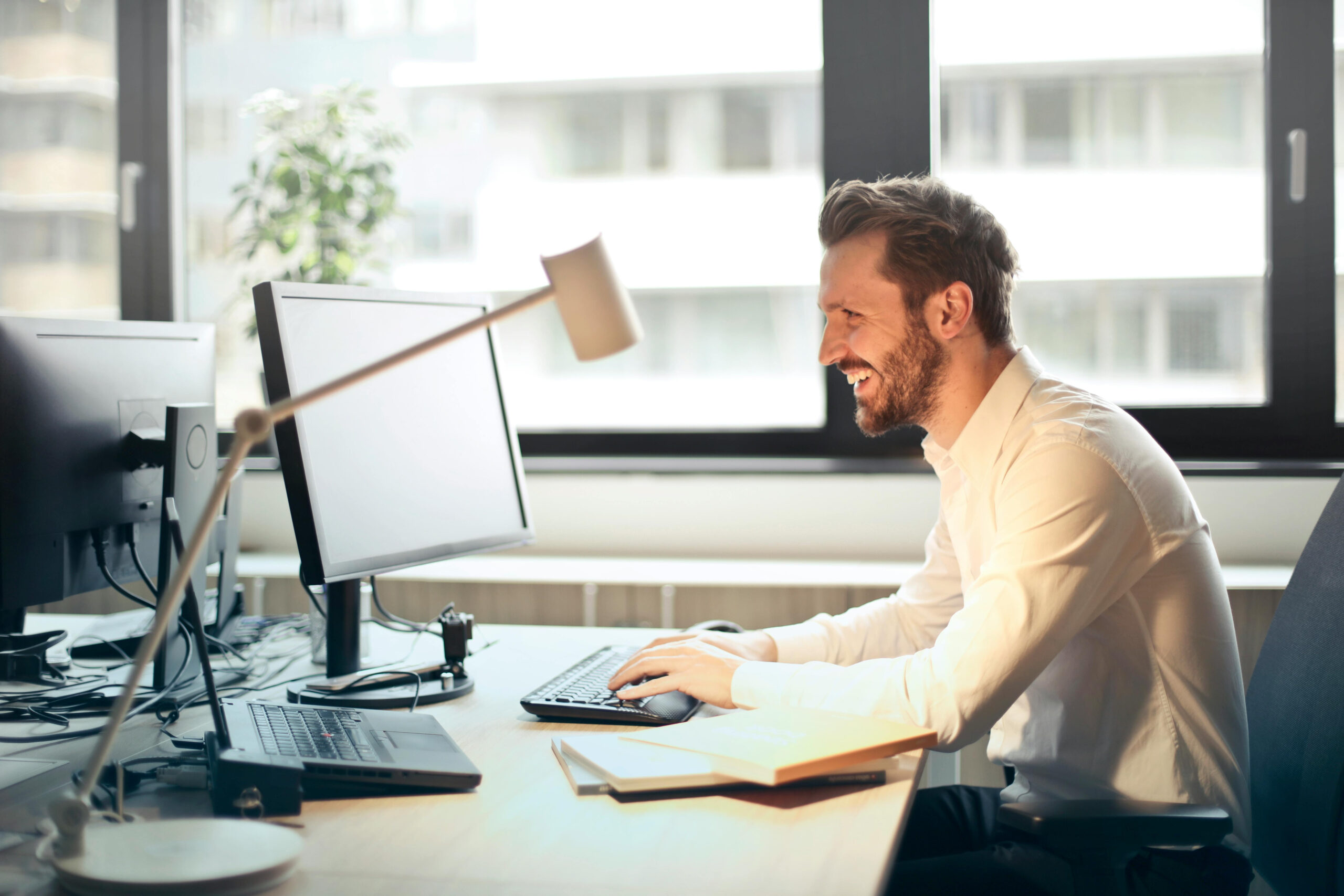 Hombre trabajando frente a una computadora en un entorno de oficina moderno y luminoso
