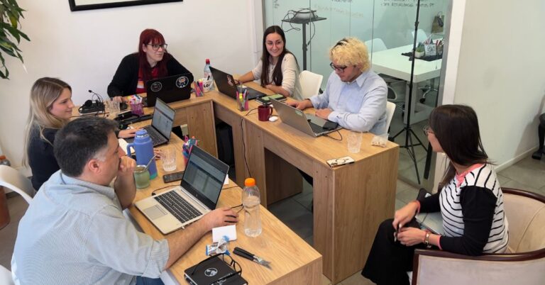 Grupo de jóvenes argentinos trabajando en un entorno educativo moderno con notebooks y recursos digitales