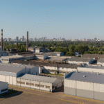 Vista aérea de un complejo industrial en Argentina con la ciudad al fondo, simbolizando inversión y competitividad