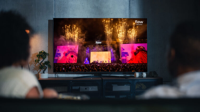 Dos personas disfrutan desde su casa la transmisión en vivo del Lollapalooza 2026 por Flow en la pantalla del televisor