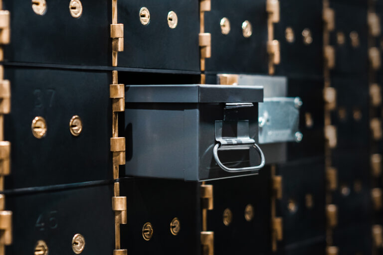 Primer plano de cajas de seguridad metálicas con cerraduras doradas, una de ellas abierta para mostrar almacenamiento seguro