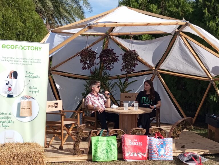 Entrevista en un espacio sustentable con emprendedores y bolsas reutilizables en exhibición, representando el impacto positivo de las empresas