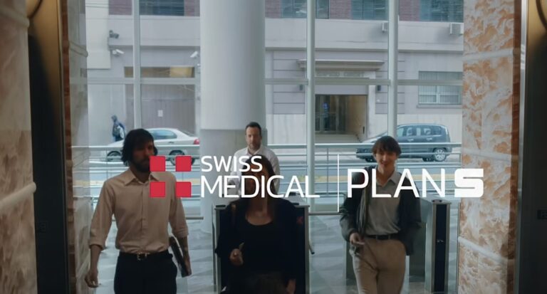 Tres jóvenes entrando a un edificio de Swiss Medical con un cartel visible de Plan S