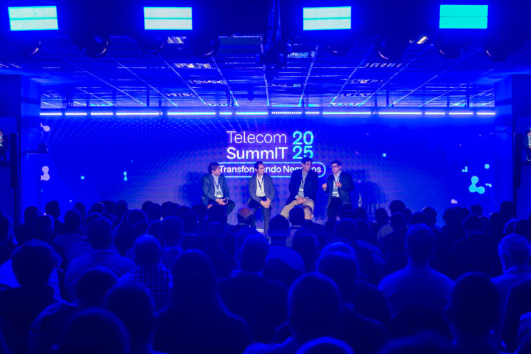 Panel de expertos en el escenario del Telecom SummIT 2025 frente a una audiencia numerosa en un evento empresarial