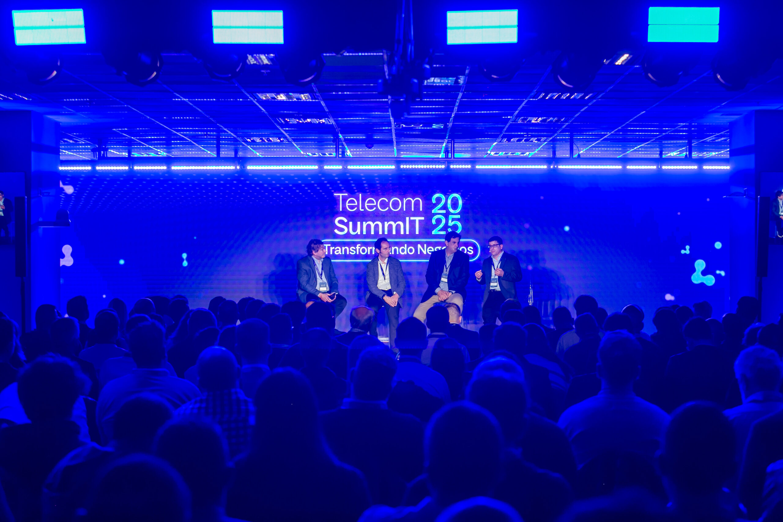Panel de expertos en el escenario del Telecom SummIT 2025 frente a una audiencia numerosa en un evento empresarial