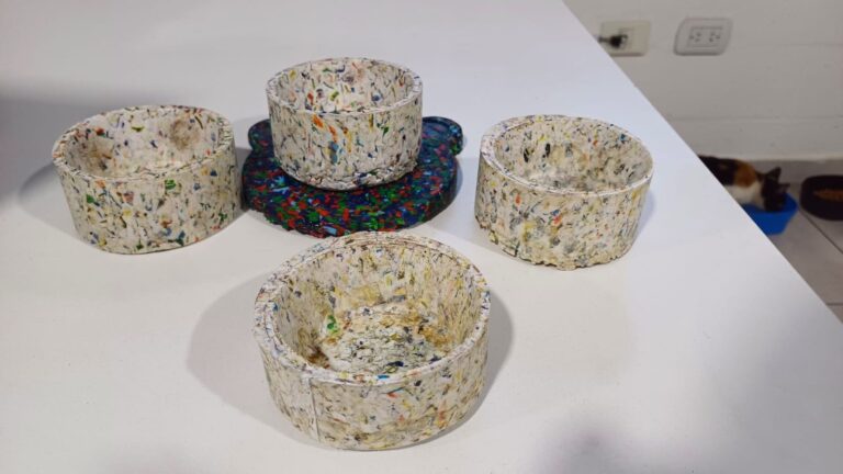 Recipientes fabricados con plástico reciclado de alto impacto, en una mesa blanca, mostrando diseño sostenible