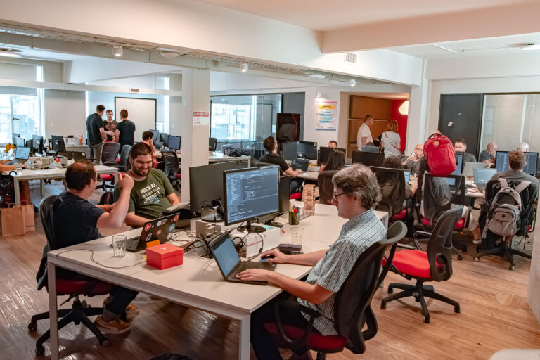 Grupo de profesionales en una oficina moderna con computadoras y laptops, trabajando en soluciones digitales y automatización