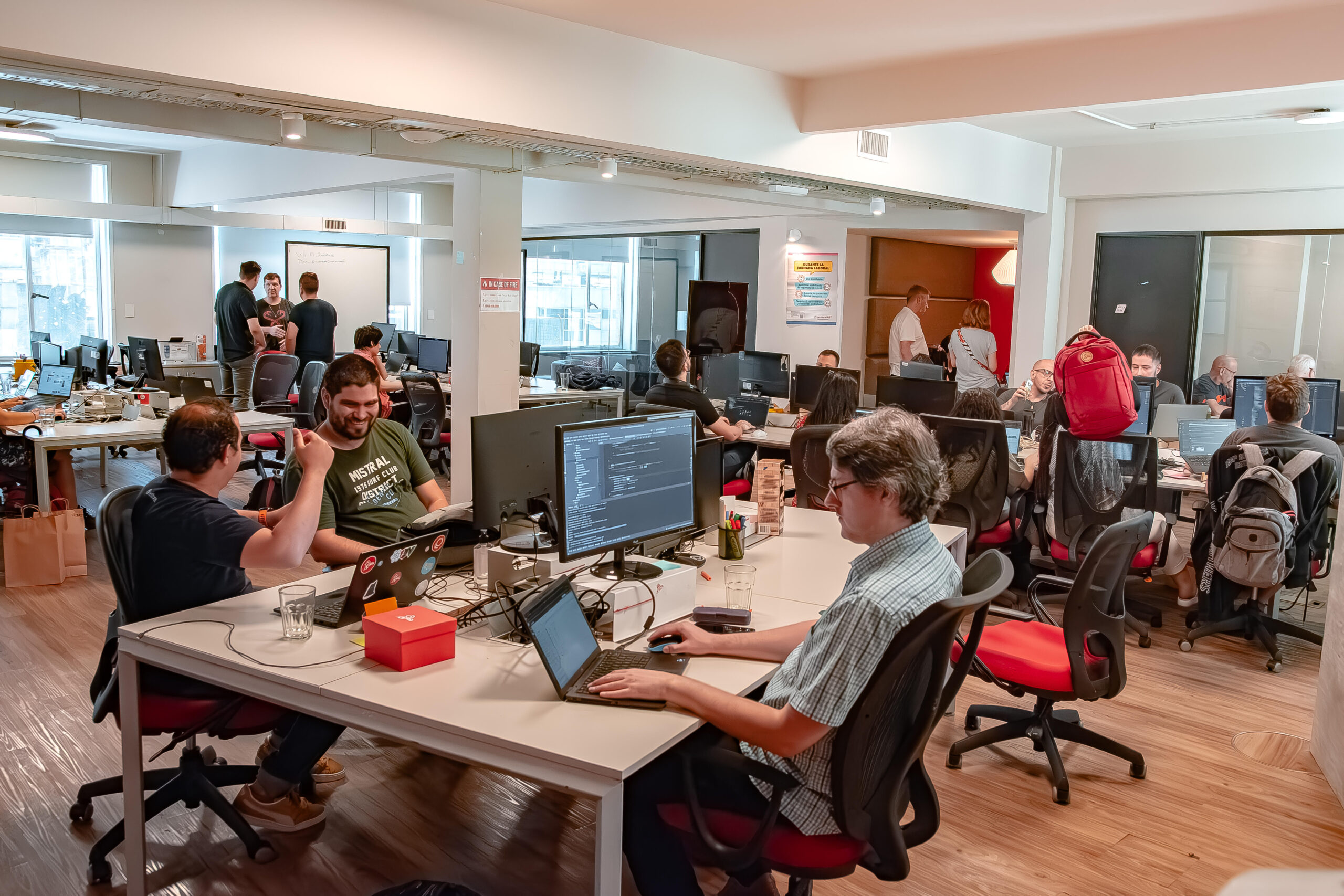Grupo de profesionales en una oficina moderna con computadoras y laptops, trabajando en soluciones digitales y automatización