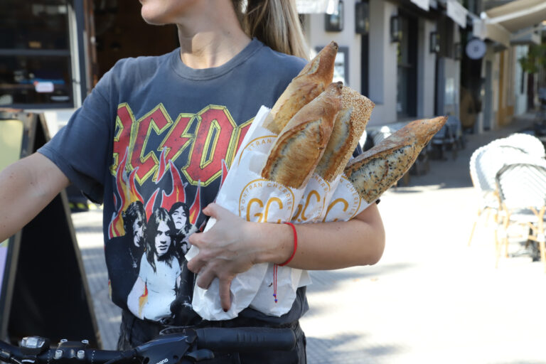 Persona sostiene baguettes francesas de la panadería Gontran Cherrier en Argentina, en un entorno urbano al aire libre