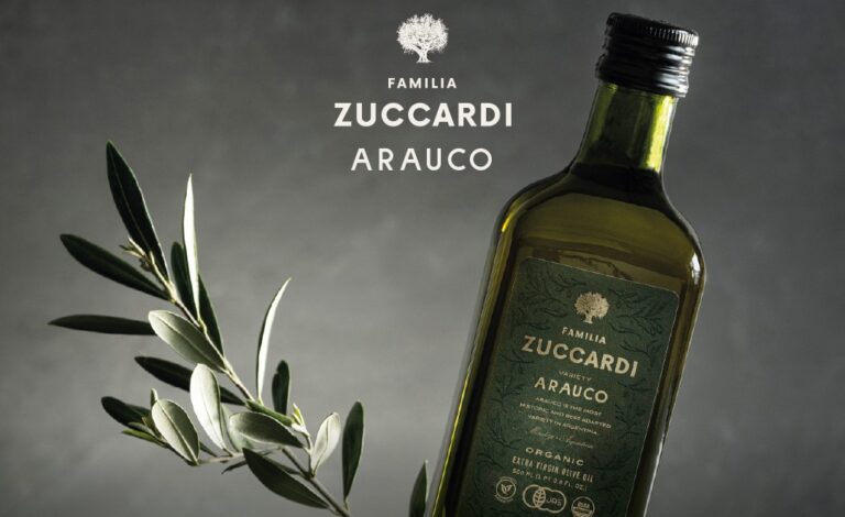 Botella de aceite de oliva extra virgen Arauco de Familia Zuccardi junto a una rama de olivo, destacando su calidad orgánica y premios internacionales