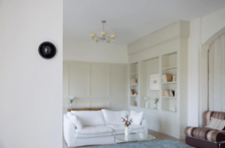 Cámara de seguridad instalada en la pared de un living luminoso con sillón blanco y estanterías