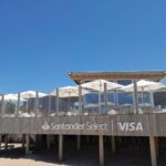 Parador de playa con sombrillas y cartelería de Santander Select y Visa en la Costa Atlántica argentina
