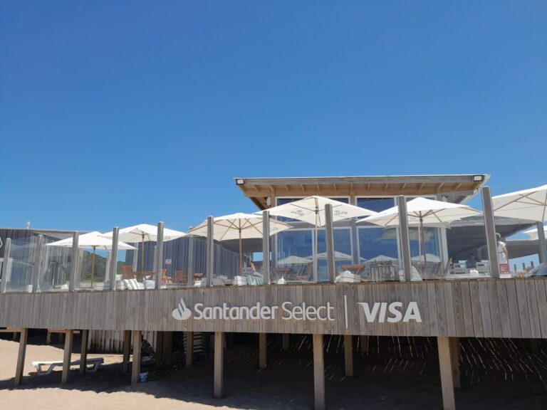 Parador de playa con sombrillas y cartelería de Santander Select y Visa en la Costa Atlántica argentina