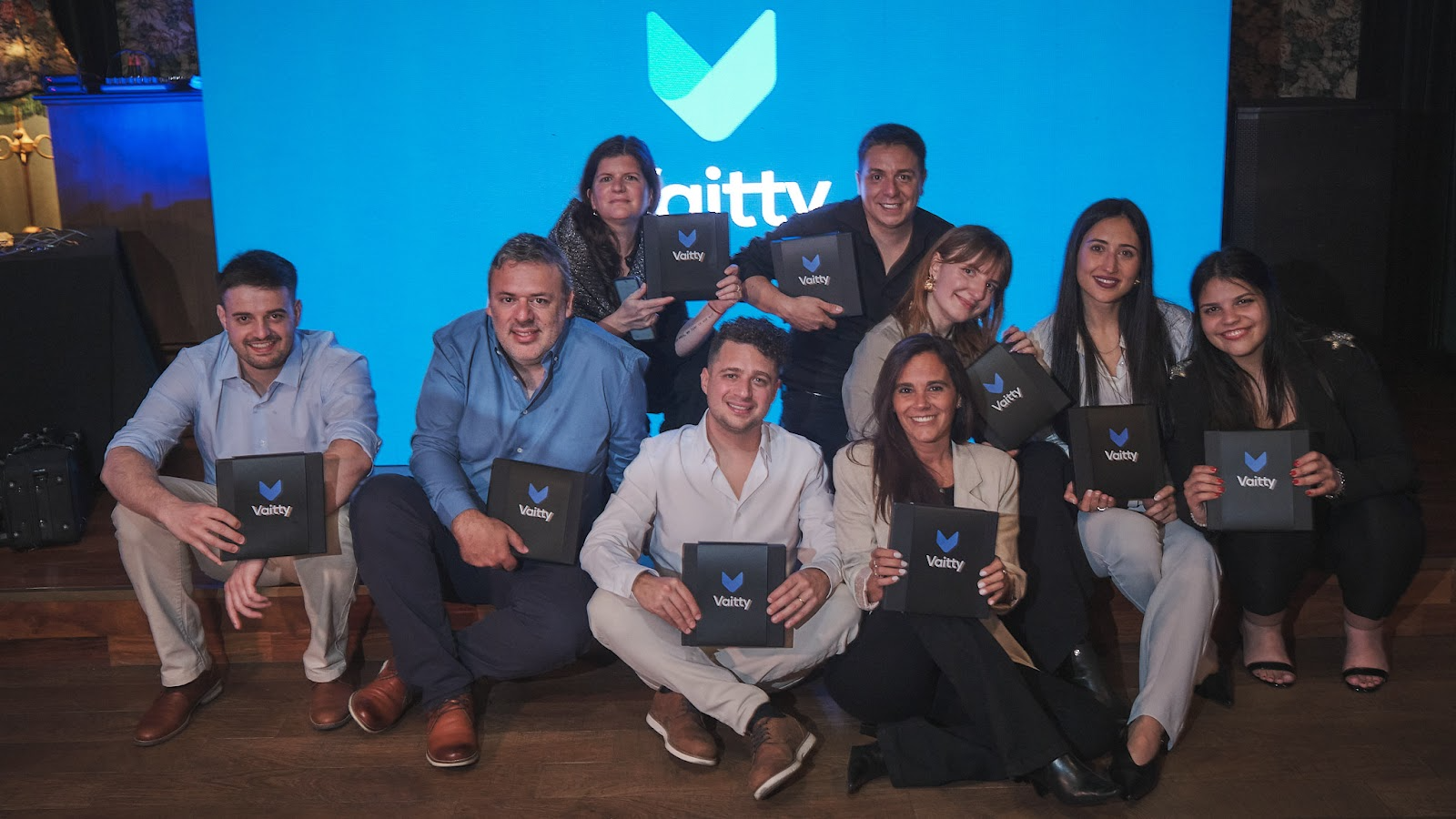 Integrantes de Vaitty posando en un evento con el logo de la startup insurtech de fondo