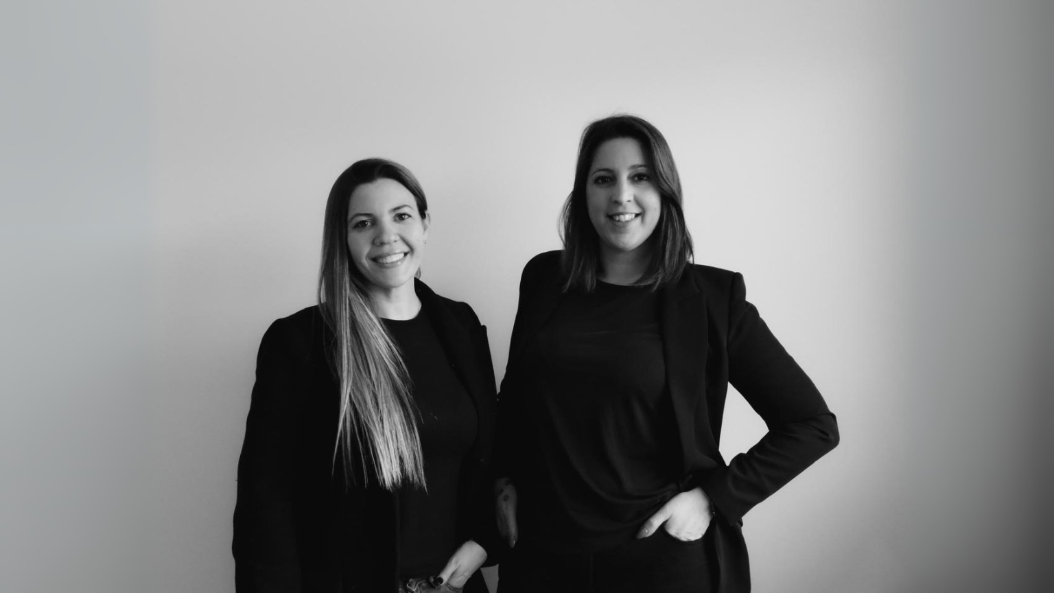 Dos diseñadoras argentinas posando juntas en retrato profesional blanco y negro