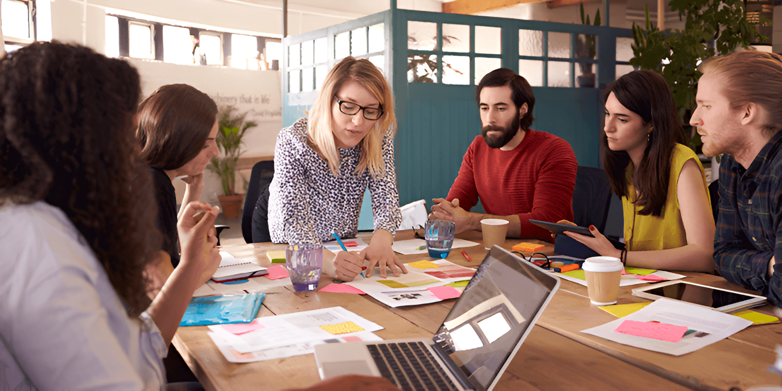 Grupo de profesionales jóvenes reunidos en una oficina compartiendo ideas y estrategias de negocio