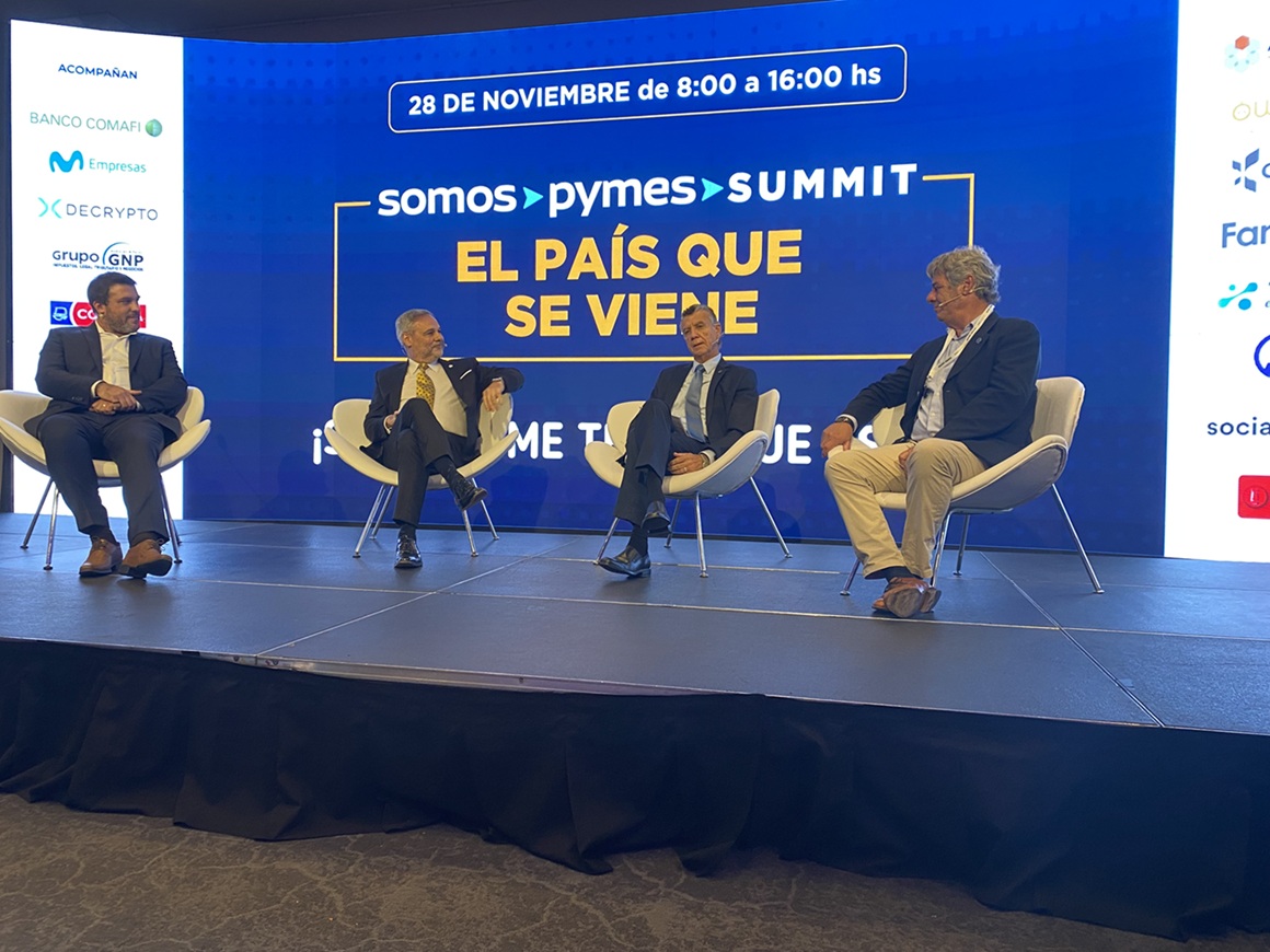 Cuatro oradores sentados en el escenario durante el Summit «El País que se Viene» de Somos Pymes, con la pantalla principal del evento de fondo