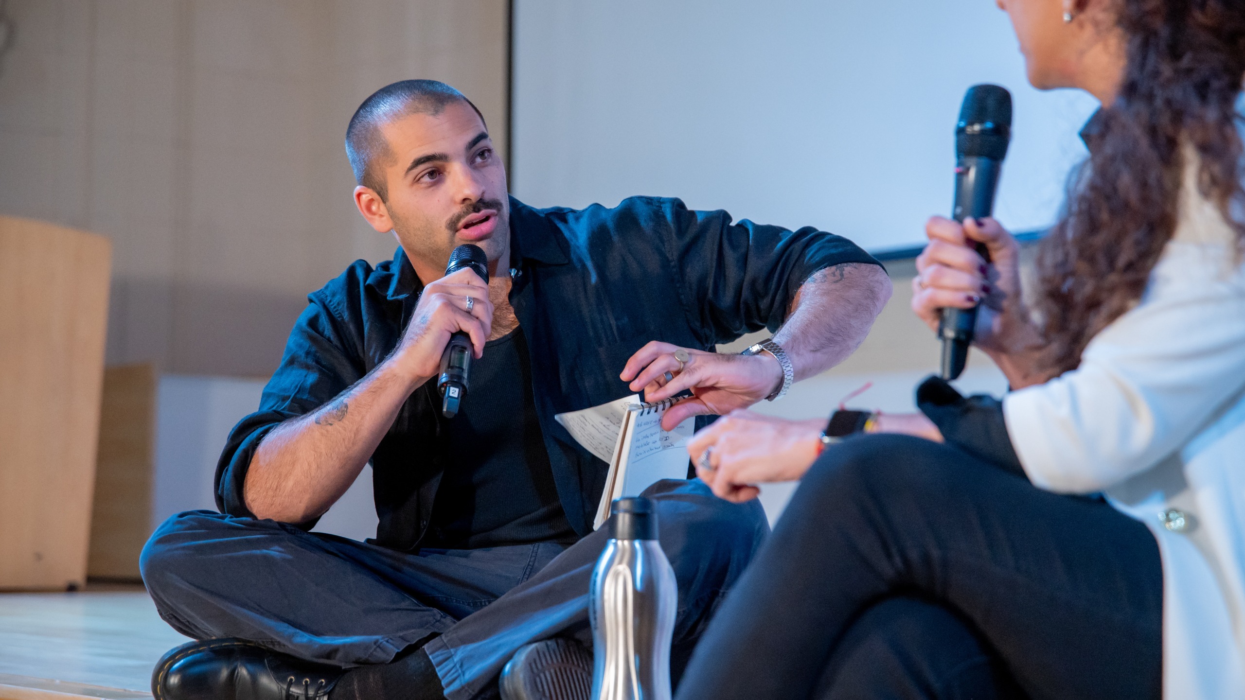 Dos personas conversando en un escenario con micrófonos en mano durante un encuentro vinculado al mundo emprendedor