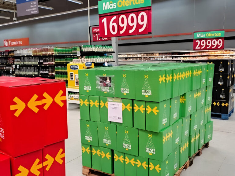 Pallets de cajas navideñas verdes y rojas exhibidas en un supermercado, listas para la venta durante la temporada festiva