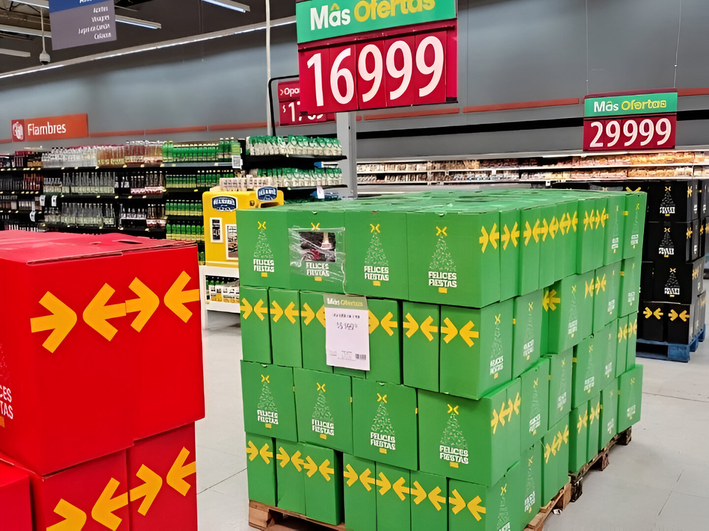 Pallets de cajas navideñas verdes y rojas exhibidas en un supermercado, listas para la venta durante la temporada festiva