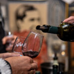 Primer plano de una copa siendo servida con vino tinto durante la noche de degustación de más de 50 vinos orgánicos organizada por Vios en la Botica del Ángel