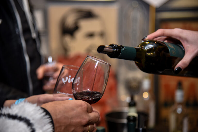 Primer plano de una copa siendo servida con vino tinto durante la noche de degustación de más de 50 vinos orgánicos organizada por Vios en la Botica del Ángel
