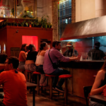 Interior de Saigón Noodle Bar con clientes disfrutando de la propuesta gastronómica en un ambiente nocturno, cálido y animado en Buenos Aires
