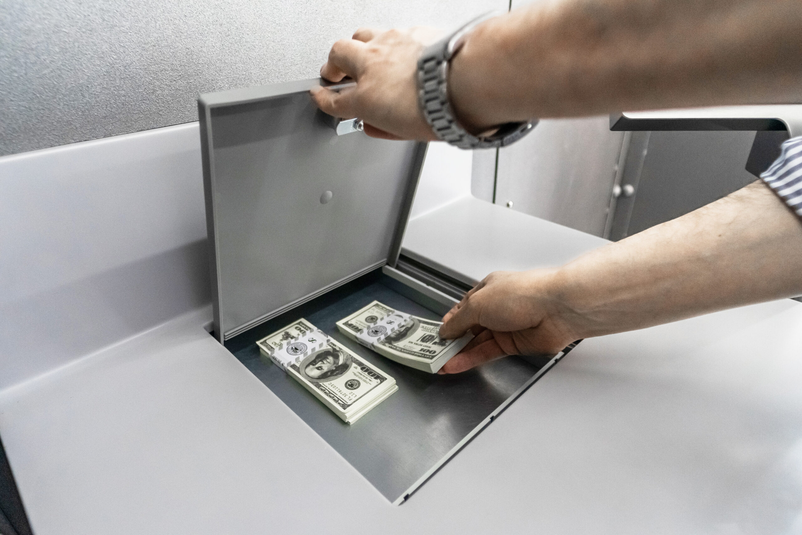 Manos guardando dinero en efectivo dentro de una caja de seguridad, en el marco de recomendaciones para cuidar ahorros y valores durante las vacaciones
