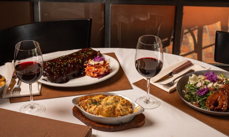 Mesa servida con platos gourmet y copas de vino tinto en Villegas Resto durante el servicio de mediodía