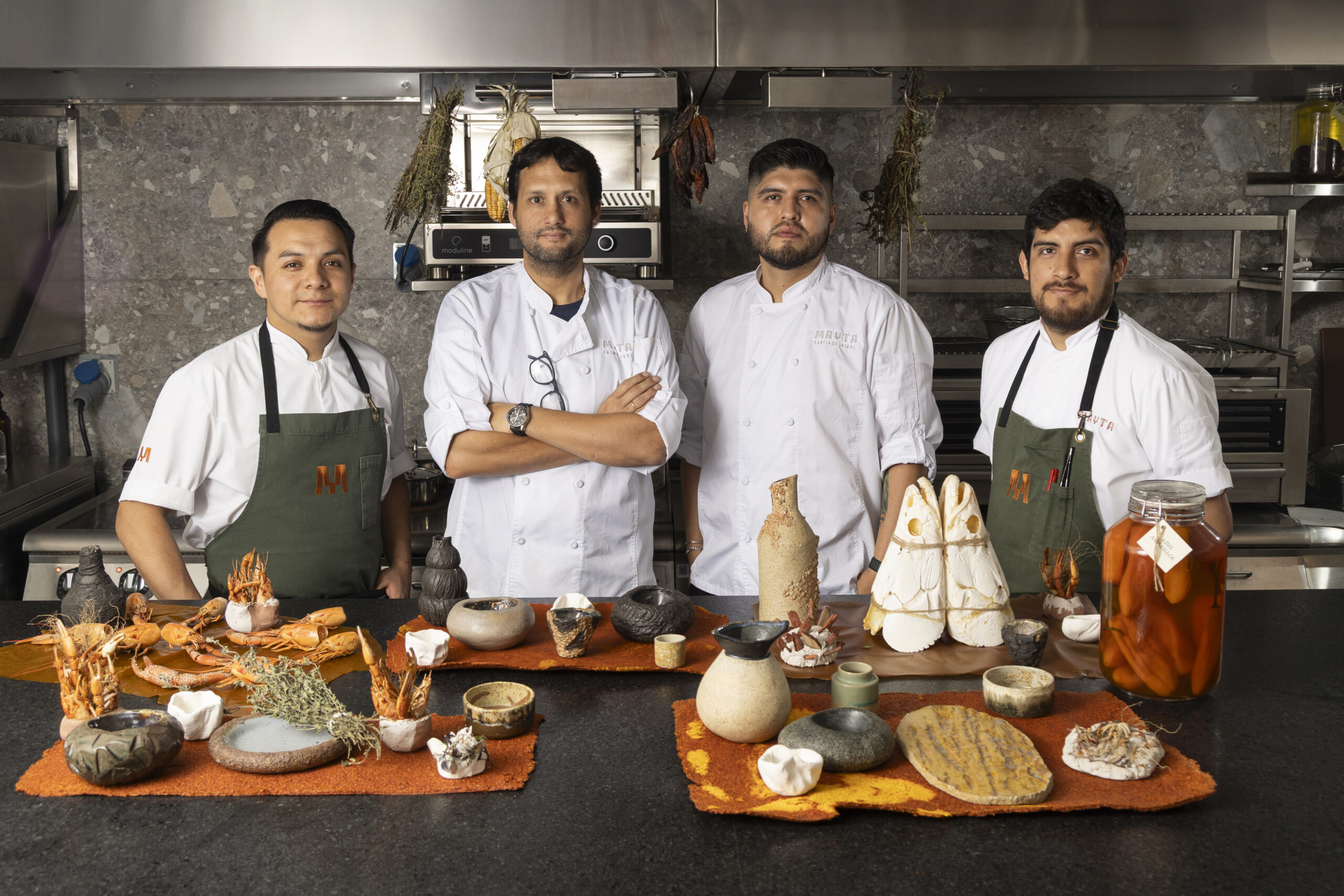 Equipo de chefs de Yachay Centro en cocina profesional junto a una mesa con platos de autor y productos regionales argentinos