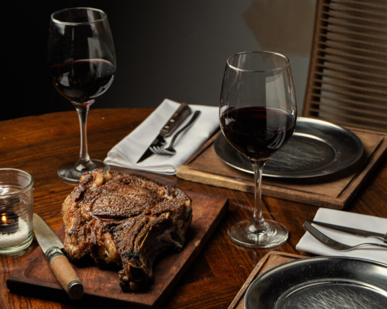 Mesa preparada con carnes al fuego y copas de vino tinto para una cena especial de San Valentín en Somos Asado junto a vinos de Ernesto Catena